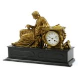 French gilt metal and black slate mantle clock striking on a bell and mounted with a female reading,