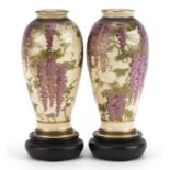Pair of Japanese Satsuma pottery vases raised on hardwood stands each hand painted with wisteria,