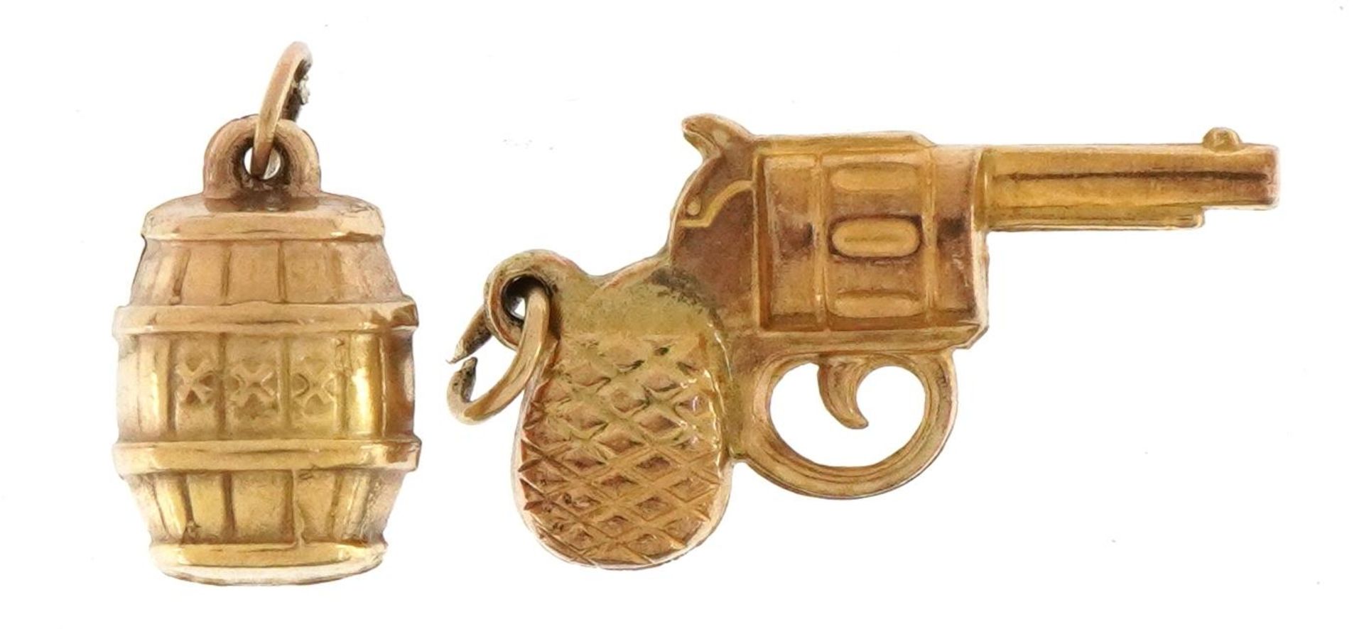 Two 9ct gold charms comprising gunpowder barrel and revolver, the largest 2.5cm high, total 1.9g