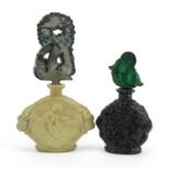 Two Bohemian Art Deco malachite glass scent bottles with stoppers, each moulded with figures, the