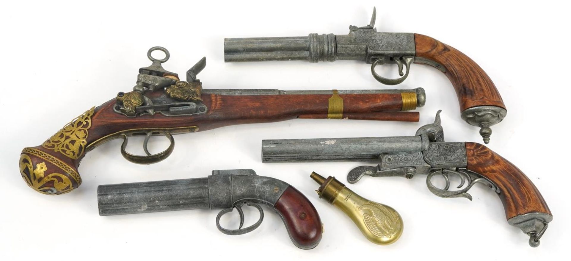 Four decorative flintlock and percussion pistols and a powder flask, the largest 42cm in length