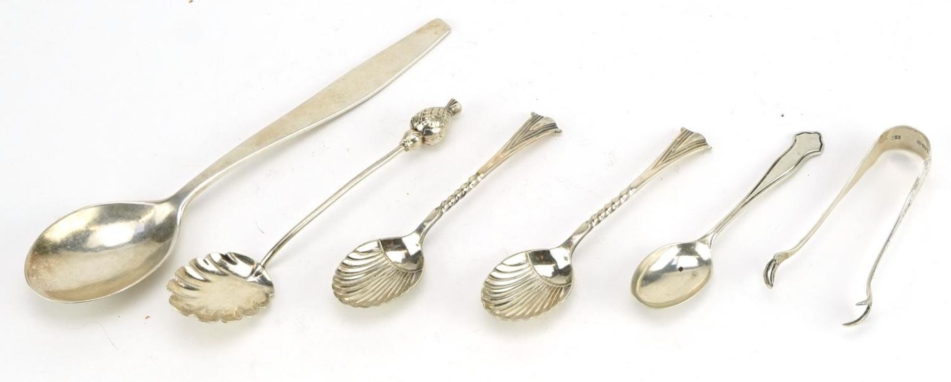 Five silver spoons and a pair of silver sugar tongs, three with shell shaped bowls, the largest 19cm