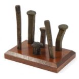 Six antique Stonemason's bronze chisels housed a later mahogany stand, the largest chisel 11cm in