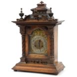Large German walnut mantle clock with brass face having applied mask and silvered chapter ring,