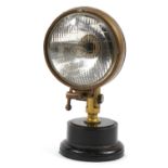 Vintage CAM brass and black enamel fire engine headlight mounted on a circular plinth base, 35cm