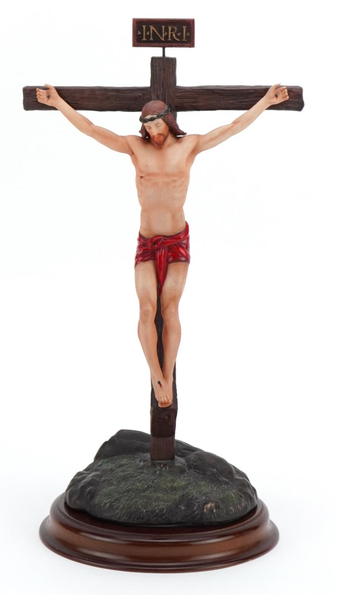 Frankin Mint porcelain model of Christ raised on a circular wood stand titled The Crucifixion,