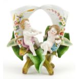 German porcelain naturalistic twin vase surmounted with Putti, hand painted with flowers and