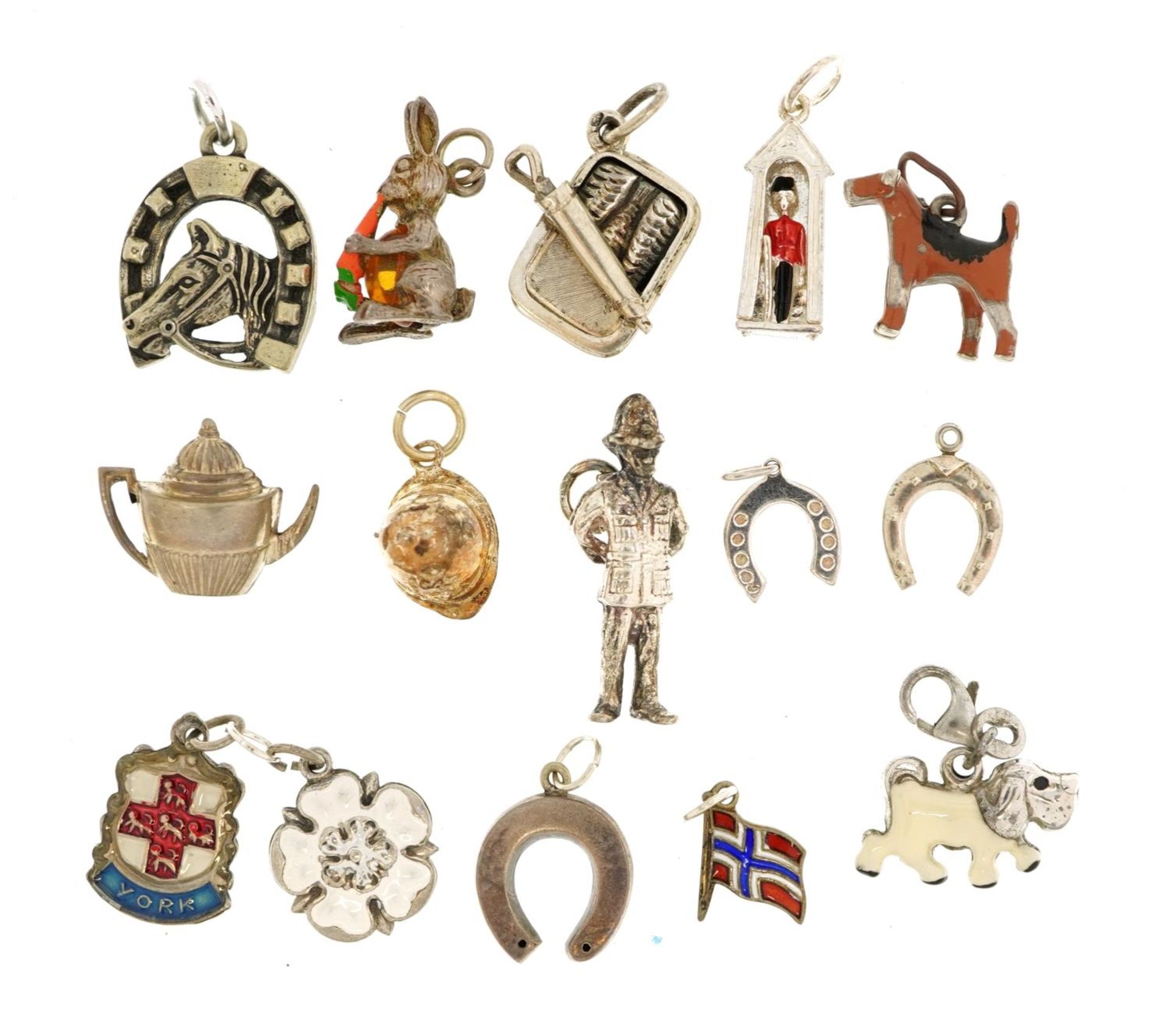 Fifteen silver charms, some enamelled, including Royal Guard in Sentry box, sardine can, dogs and