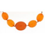 Butterscotch amber coloured graduated bead necklace, the largest bead 24.5mm in length, 92cm in