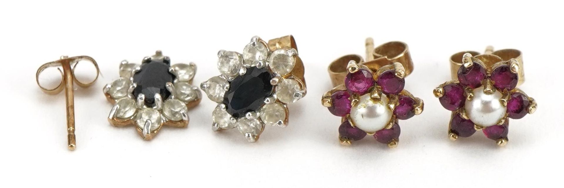 Two pairs of 9ct gold stud earrings comprising sapphire and clear stone and ruby and pearl, the