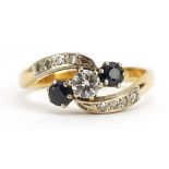 18ct gold diamond and sapphire three stone crossover ring with diamond set shoulders, the diamond