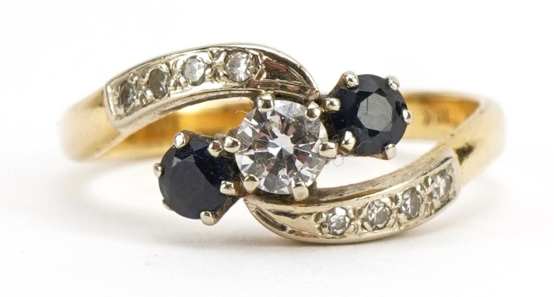 18ct gold diamond and sapphire three stone crossover ring with diamond set shoulders, the diamond