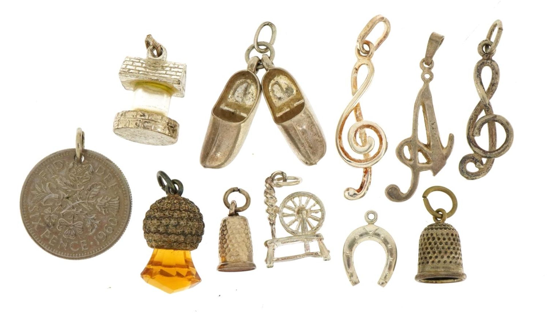 Eleven silver and white metal charms and pendants including wishing well, music notes and spinning