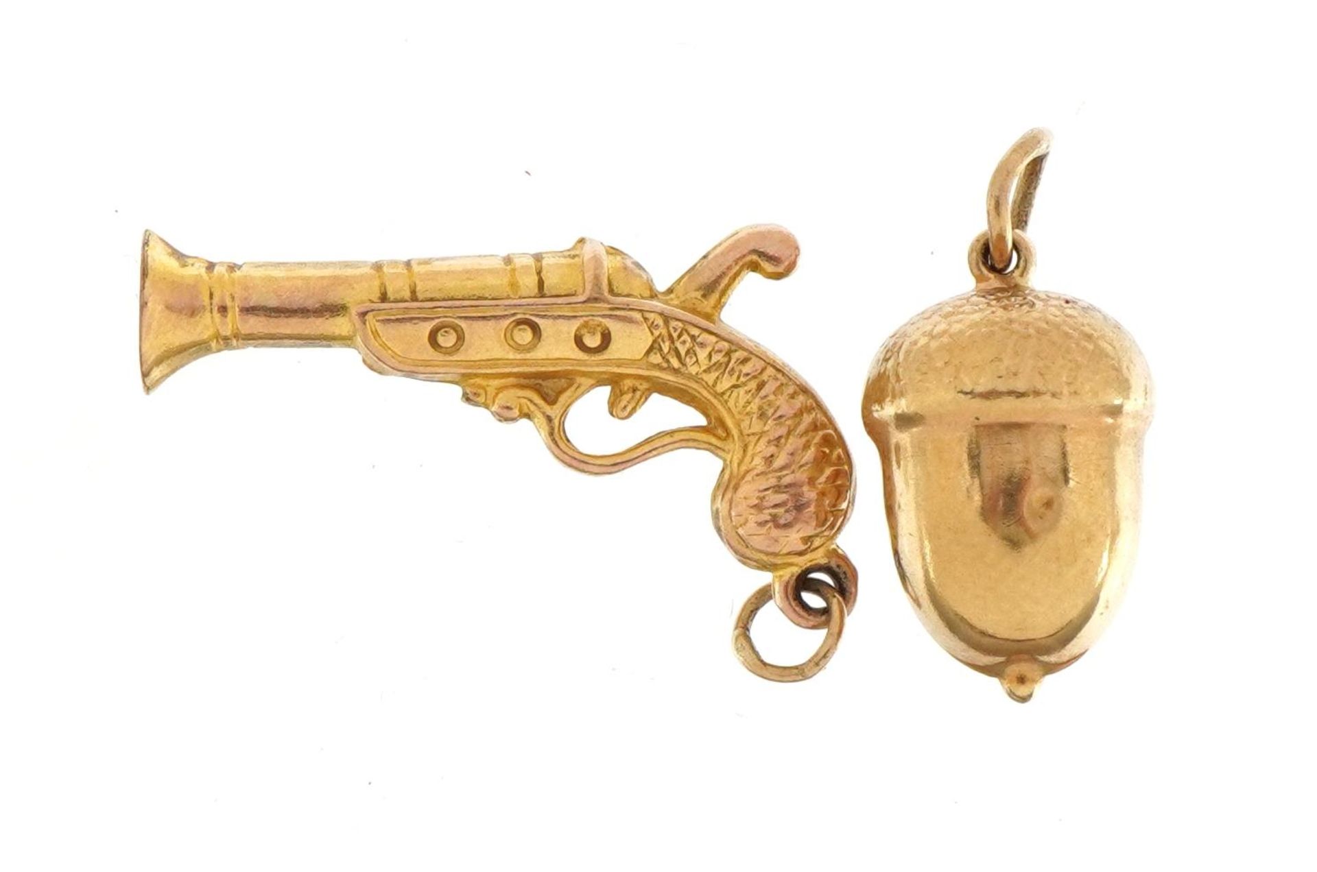 Two 9ct gold charms comprising acorn and pistol, the largest 2.6cm wide, total 1.7g : For further