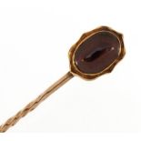 Unmarked gold cabochon red stone stickpin housed in a fitted box, 5.8cm high, 0.9g : For further