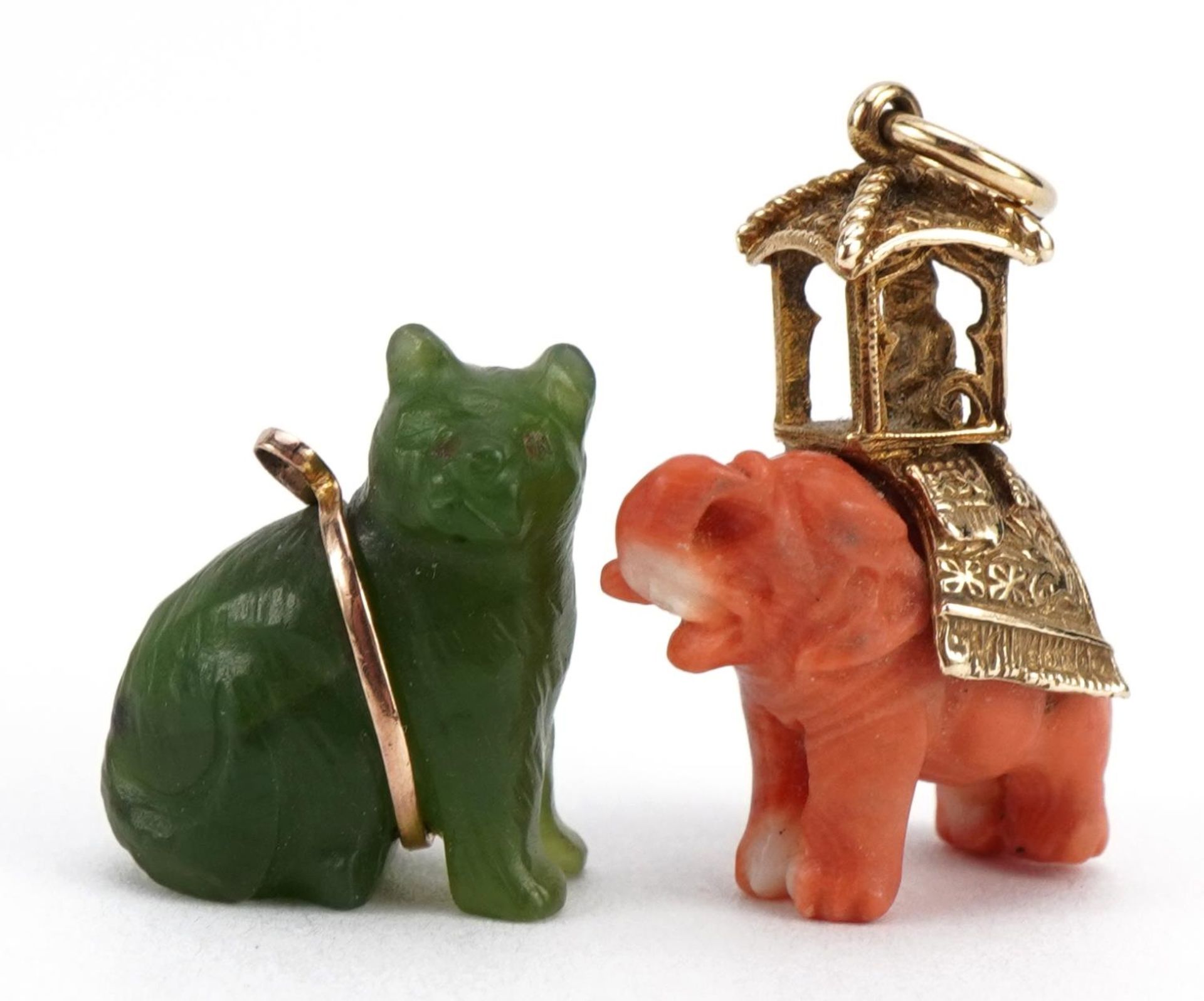 Two Chinese charms comprising carved coral elephant with 9ct gold mount and green stone cat, the
