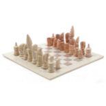 Tribal interest carved hardstone chess set with hardstone board, the largest pieces each 14cm