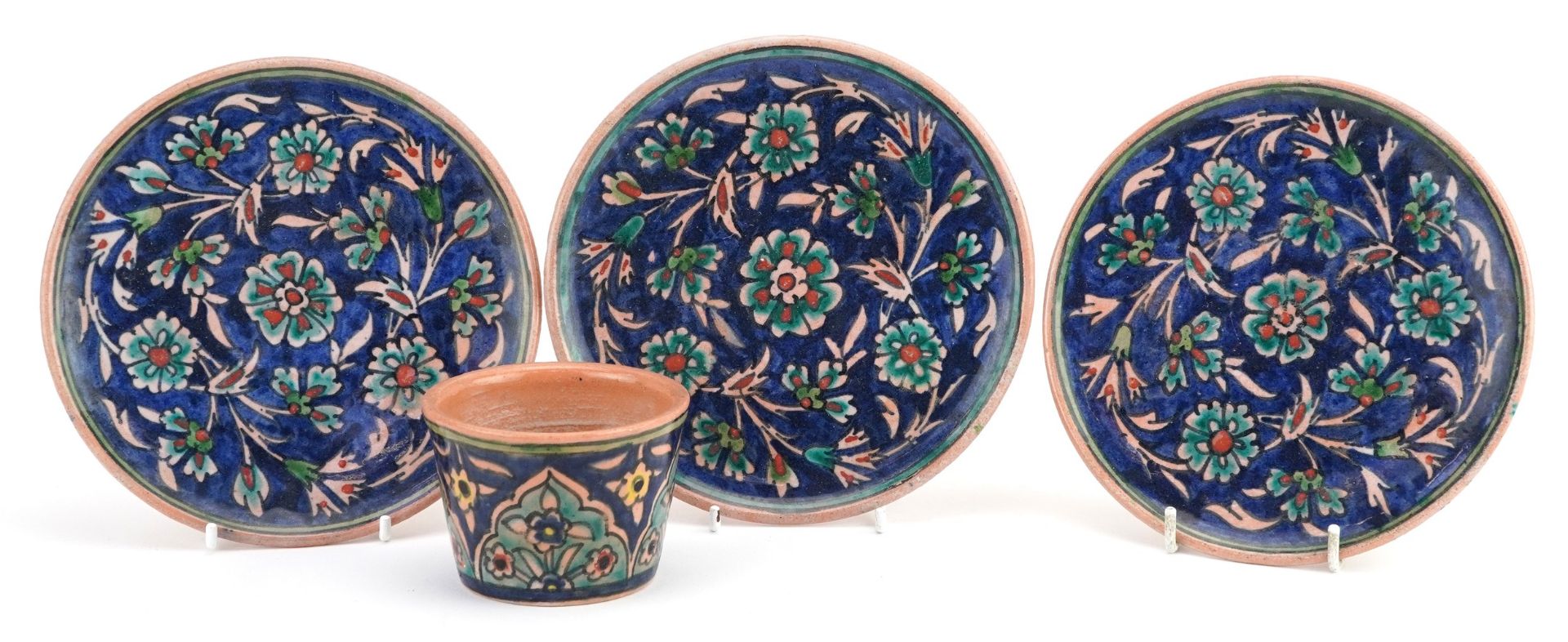 Three hand painted Isnik Palestine floral pottery plates and a similar pot, largest 16cms round :