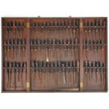 Collection of predominantly rosewood handled woodworking chisels arranged in a mahogany wall hanging