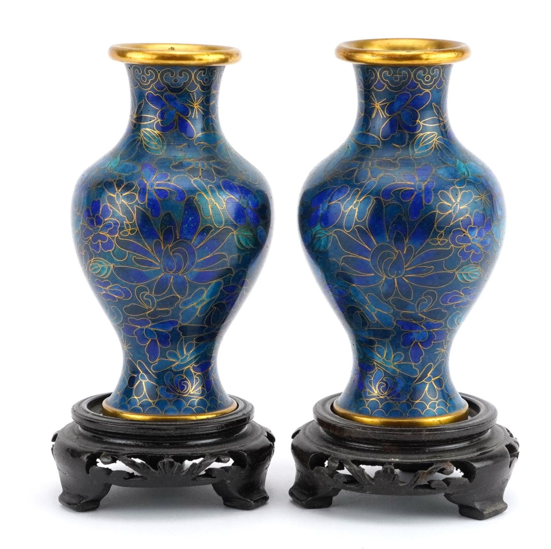 Pair of Chinese cloisonne vases raised on hardwood stands enamelled with flowers, each overall