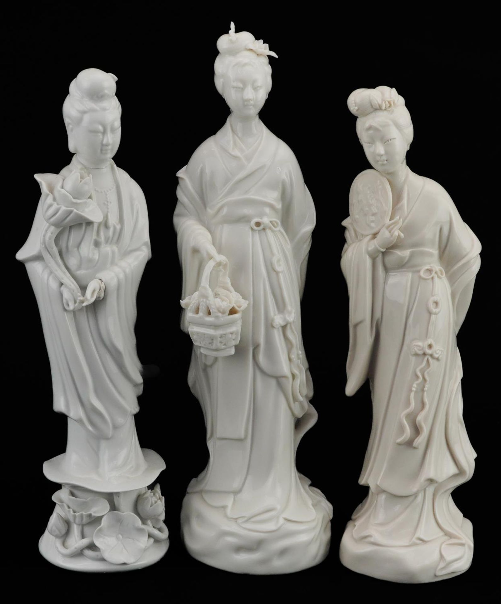 Three Chinese porcelain figures of Guanyin, each having a blanc de chine glaze, the largest 27cm