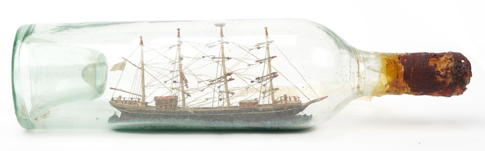 Early 20th century glass ship in a bottle housing a wooden model of a frigate, 34cm high : For