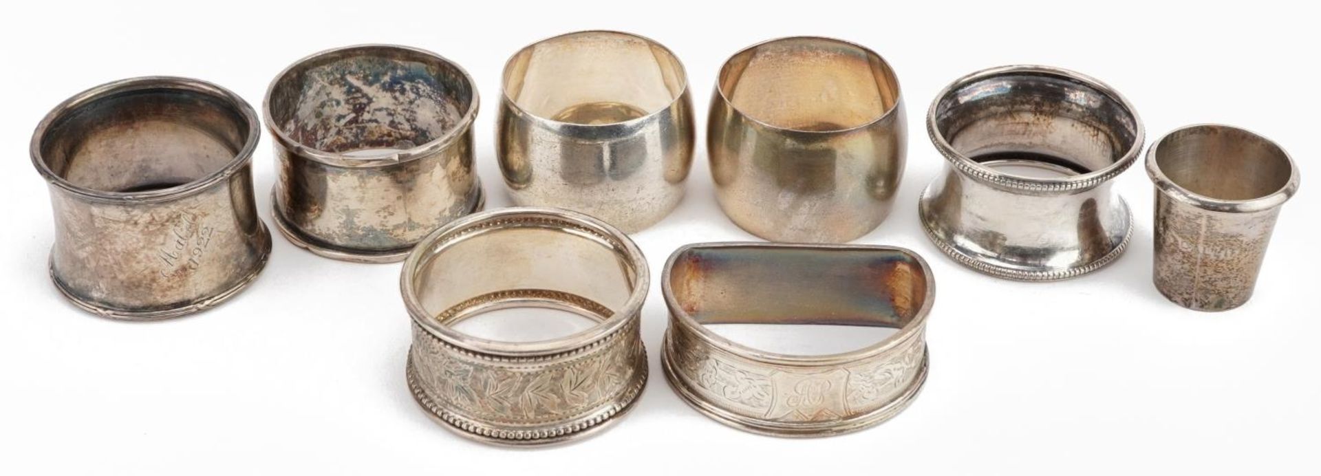 Seven Victorian and later silver napkin rings and a sterling silver thimble cup, the largest 5.5cm