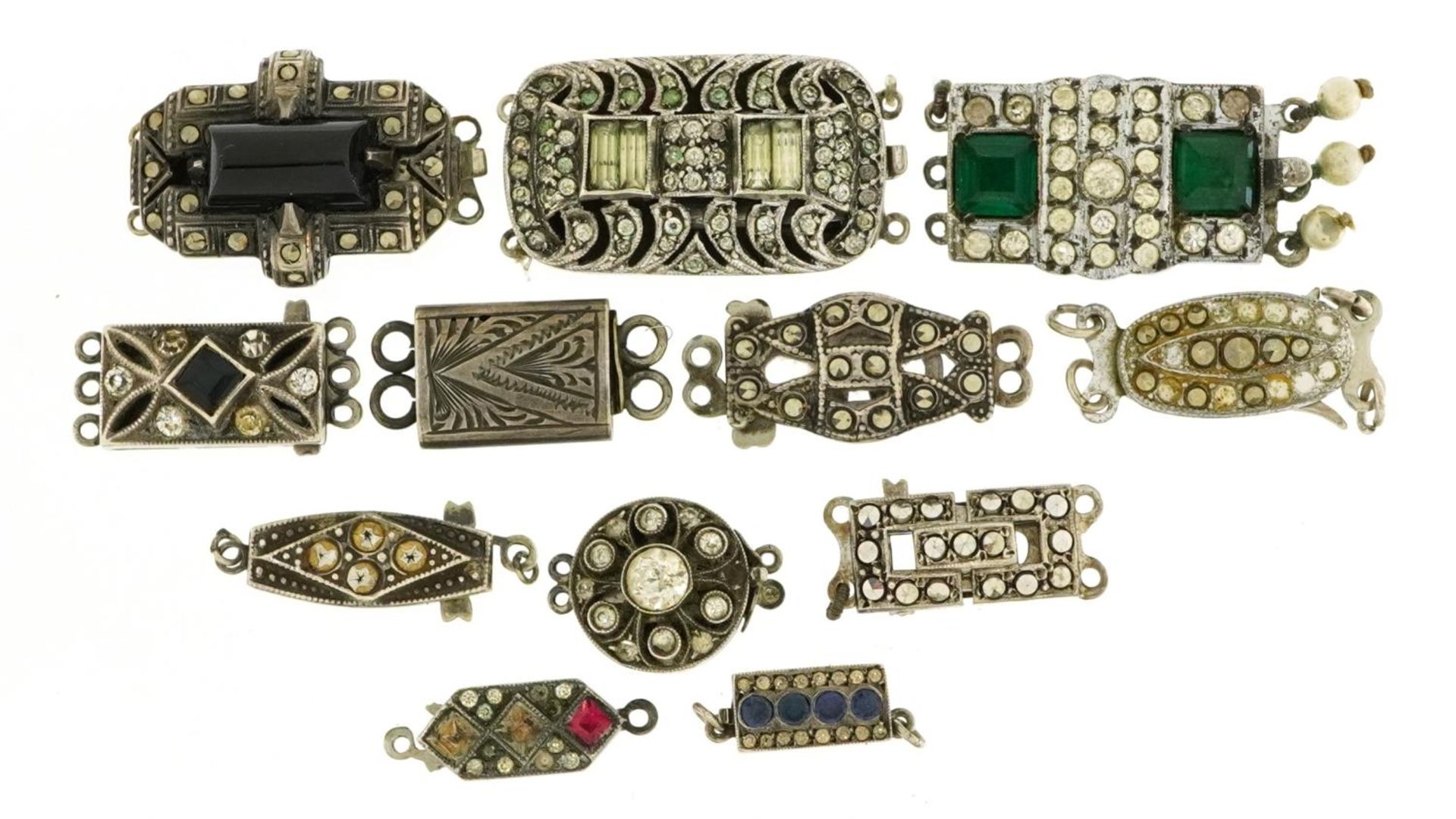 Twelve silver clasps including Art Deco marcasite and paste set examples, the largest 2.7cm wide,