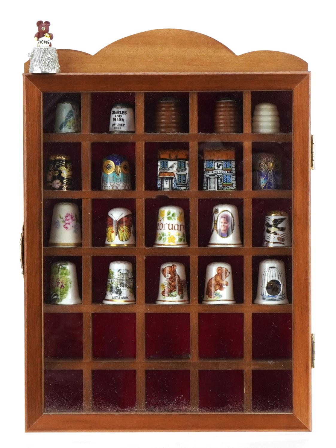 Twenty one thimbles housed in a display case including two silver and enamel and five cloisonne