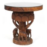 African circular centre table profusely carved with elephants and trees, 80cm high x 75cm in