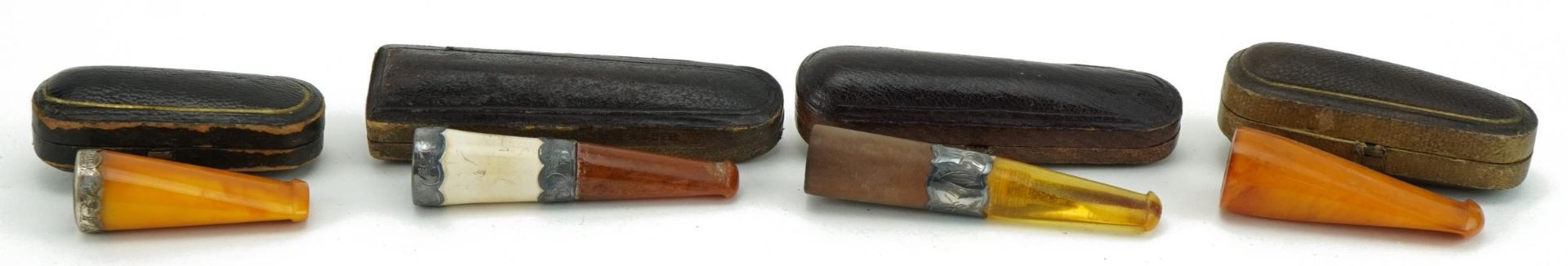 Four late 19th/early 20th century cigarette holders including two butterscotch amber examples, three