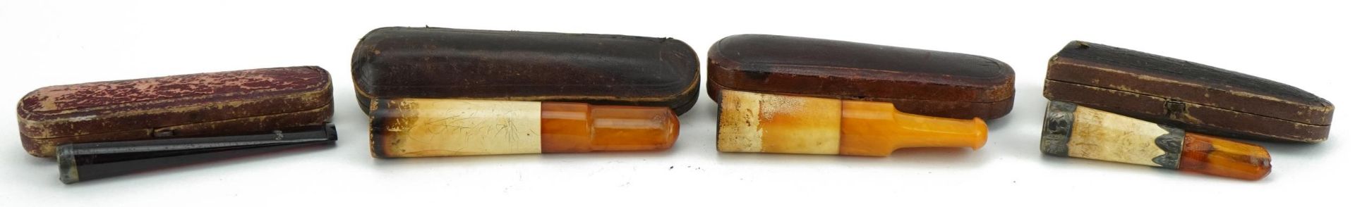 Four late 19th/early 20th century cigarette holders including butterscotch amber and cherry amber