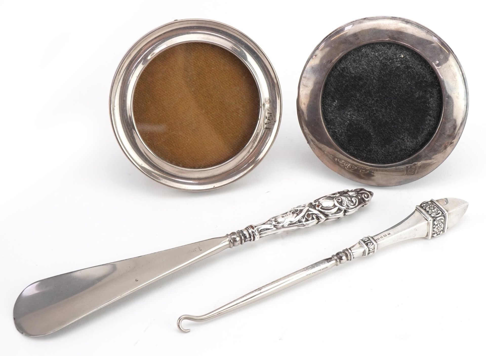 Silver objects comprising two circular silver easel photo frames and a silver handled shoe horn
