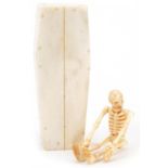 Carved bone articulated skeleton housed in a coffin, inscribed to the base of the coffin, the