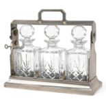 Silver plated three bottle tantalus stand with three cut glass decanters and key, 34.5cm wide :