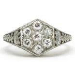 Unmarked white gold hexagonal diamond cluster ring with scrolled pierced setting, tests as 18ct