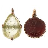 Two Islamic gold mounted hardstone pendants with engraved calligraphy, each mount indistinctly