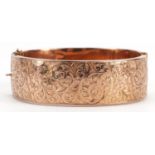 9ct rose gold hinged bangle with engraved floral decoration and safety chain, 6.3cm wide, 20.1g :