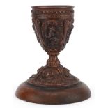 19th century gilt meta chalice decorated in relief with putti, raised on a circular oak base, with