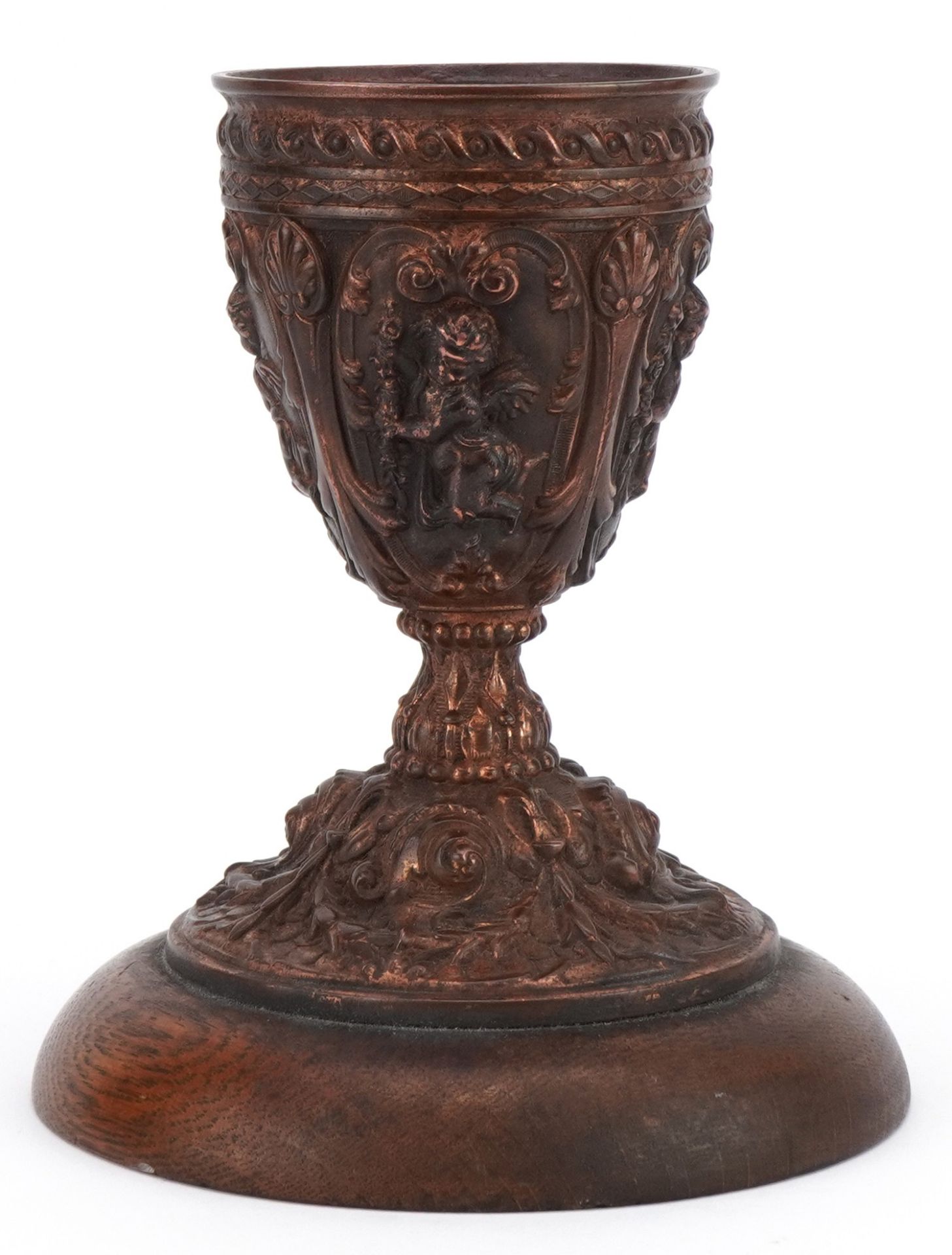 19th century gilt meta chalice decorated in relief with putti, raised on a circular oak base, with