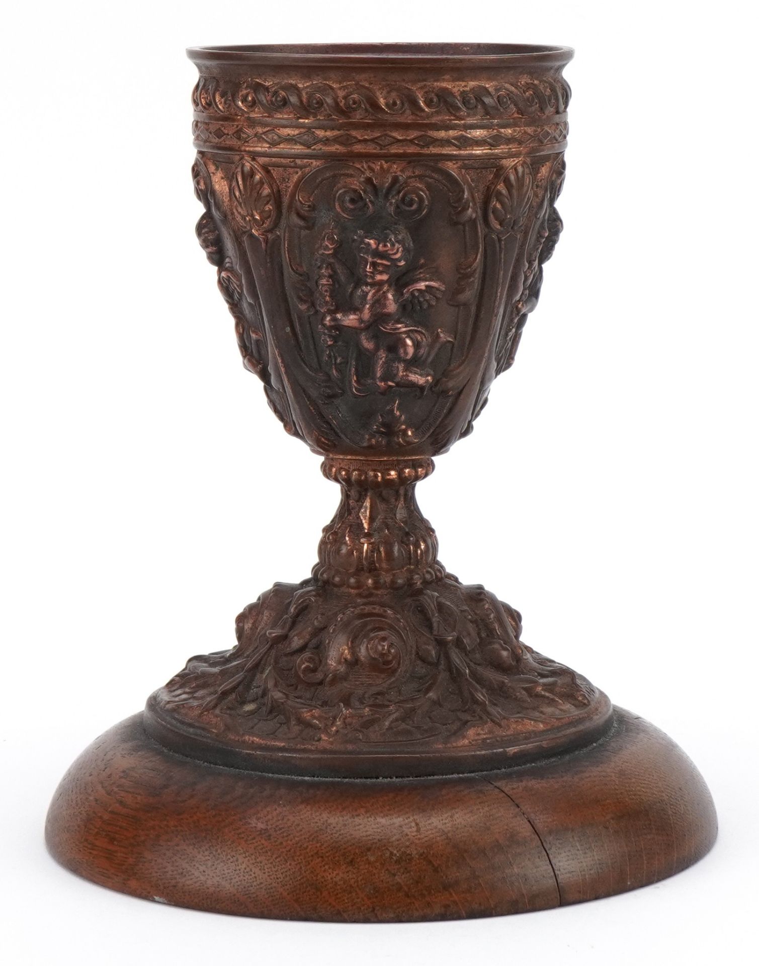 19th century gilt meta chalice decorated in relief with putti, raised on a circular oak base, with - Image 3 of 8