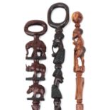 Three African hardwood walking sticks including two carved with figures, the largest 104cm in length