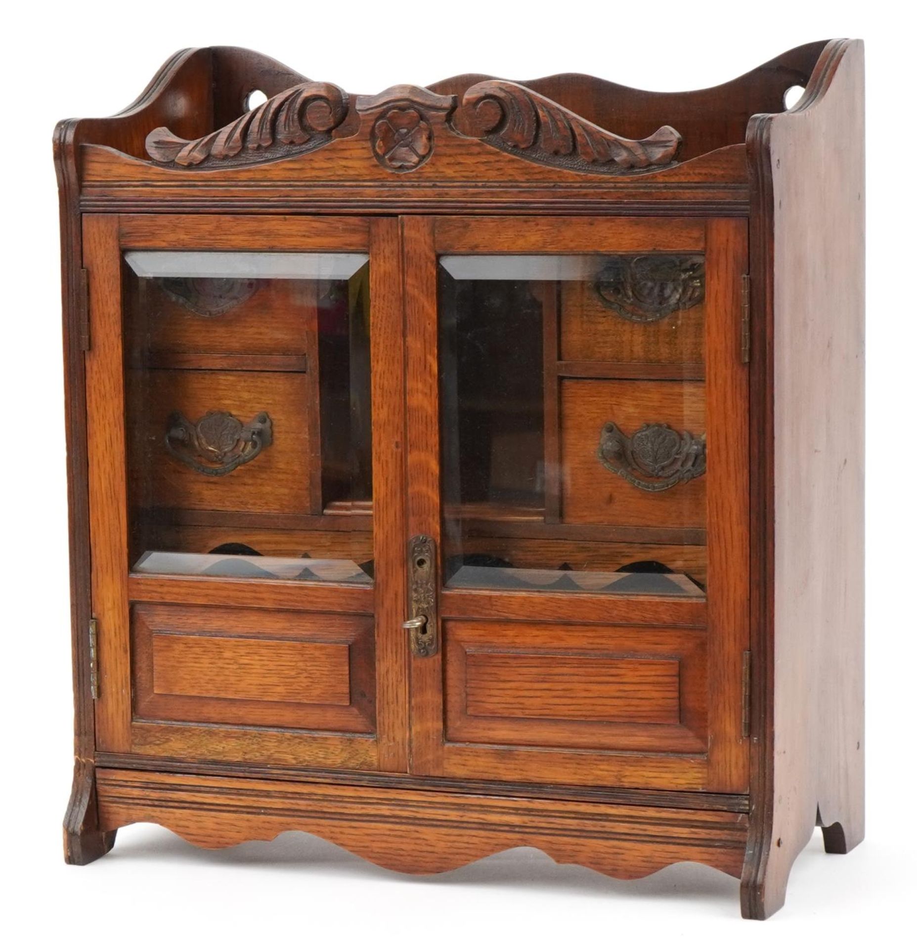 Arts & Crafts oak smoker's cabinet with a pair of glazed doors enclosing four drawers and open