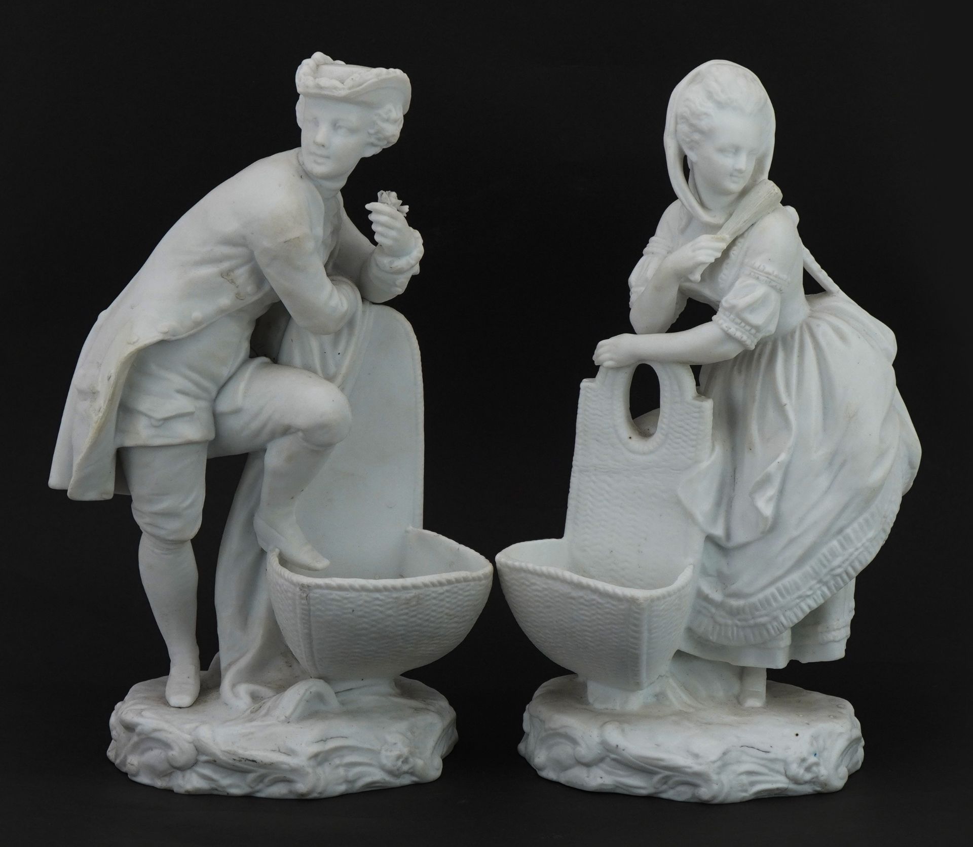 Pair of bisque porcelain figural salts in the style of Chelsea, the largest 26cm high