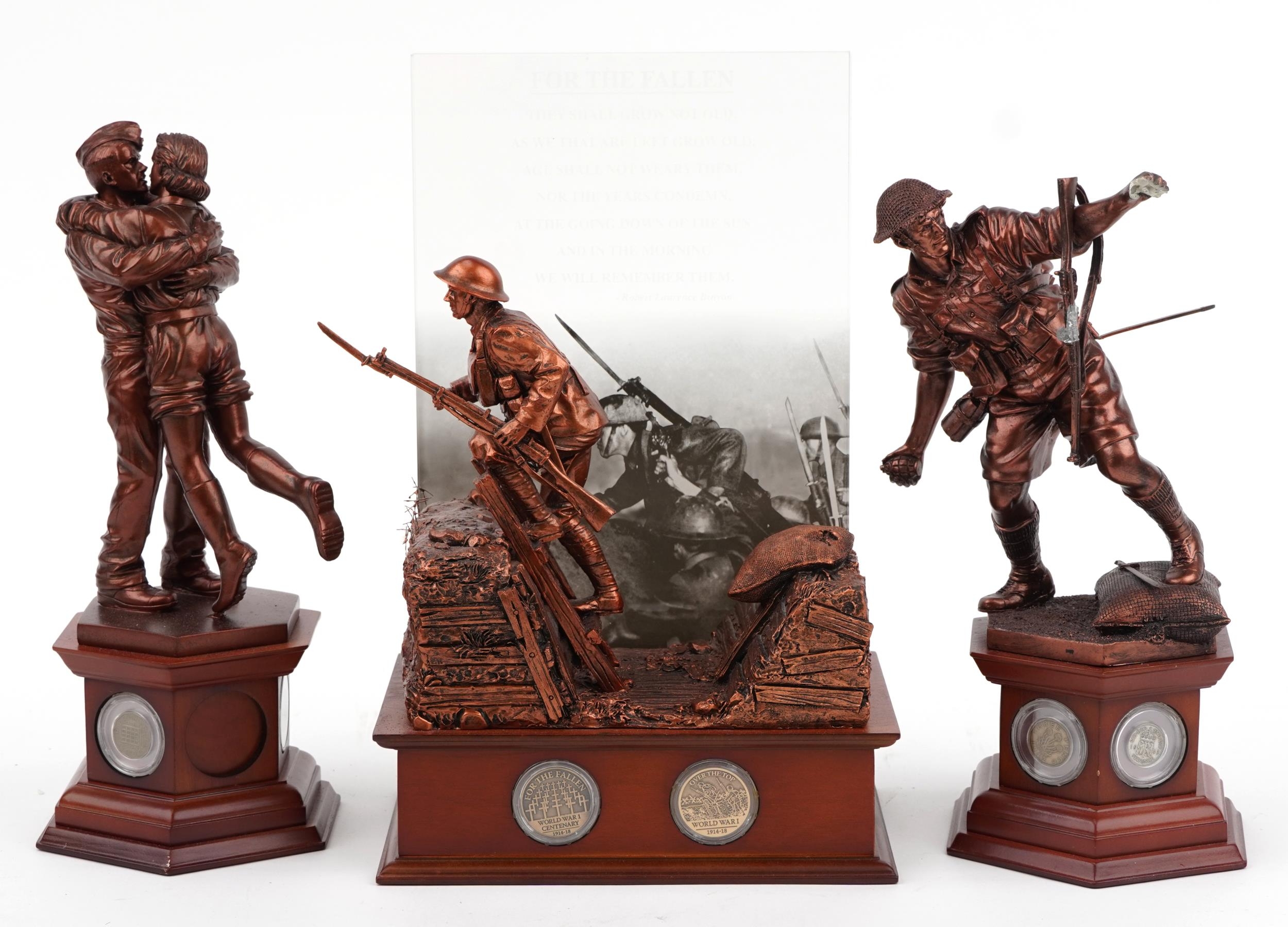 Three bronzed commemorative military figures raised on wooden bases set with coins and medallions by