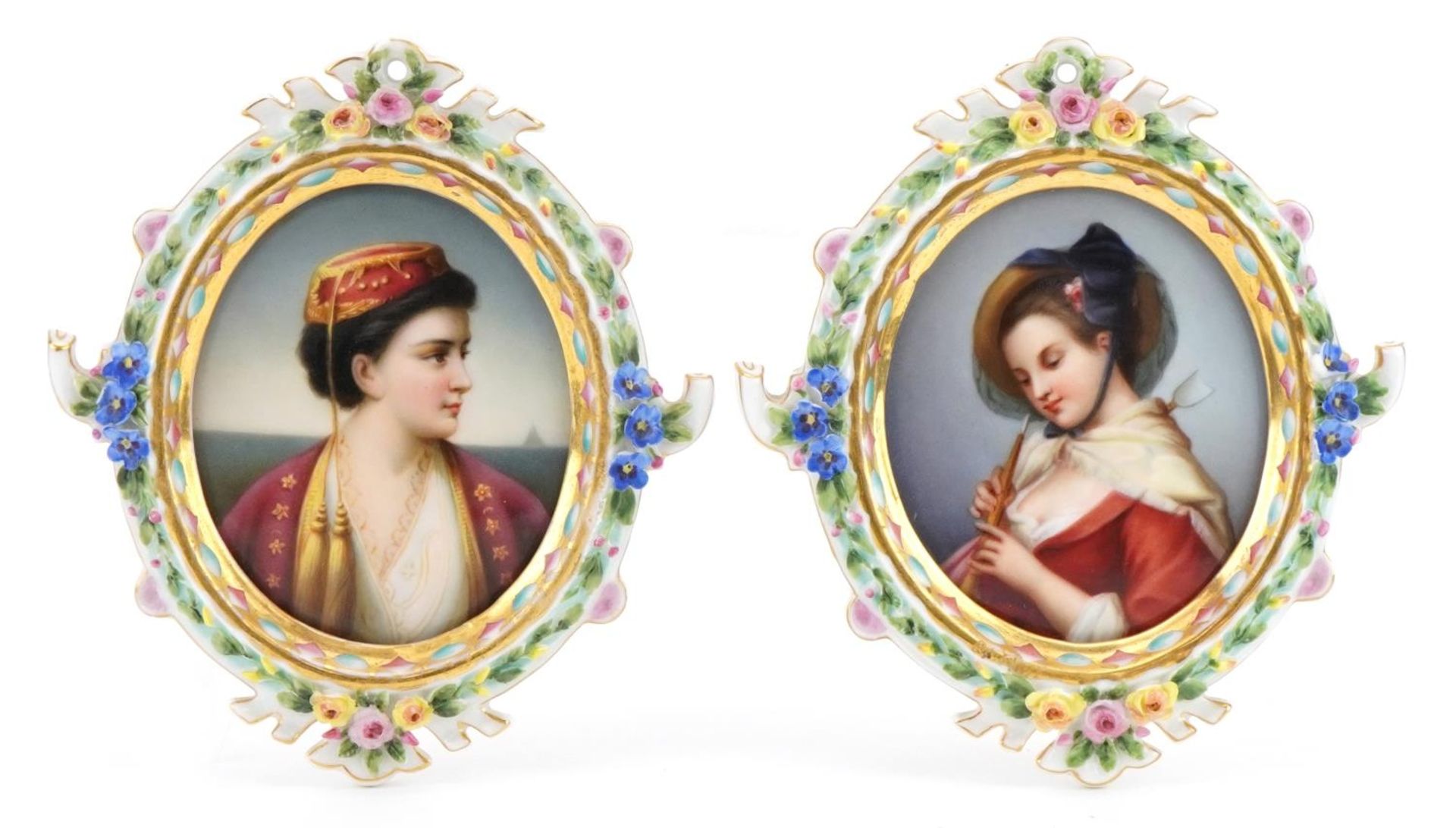 Pair of continental oval porcelain plaques hand painted with maidens housed in floral encrusted