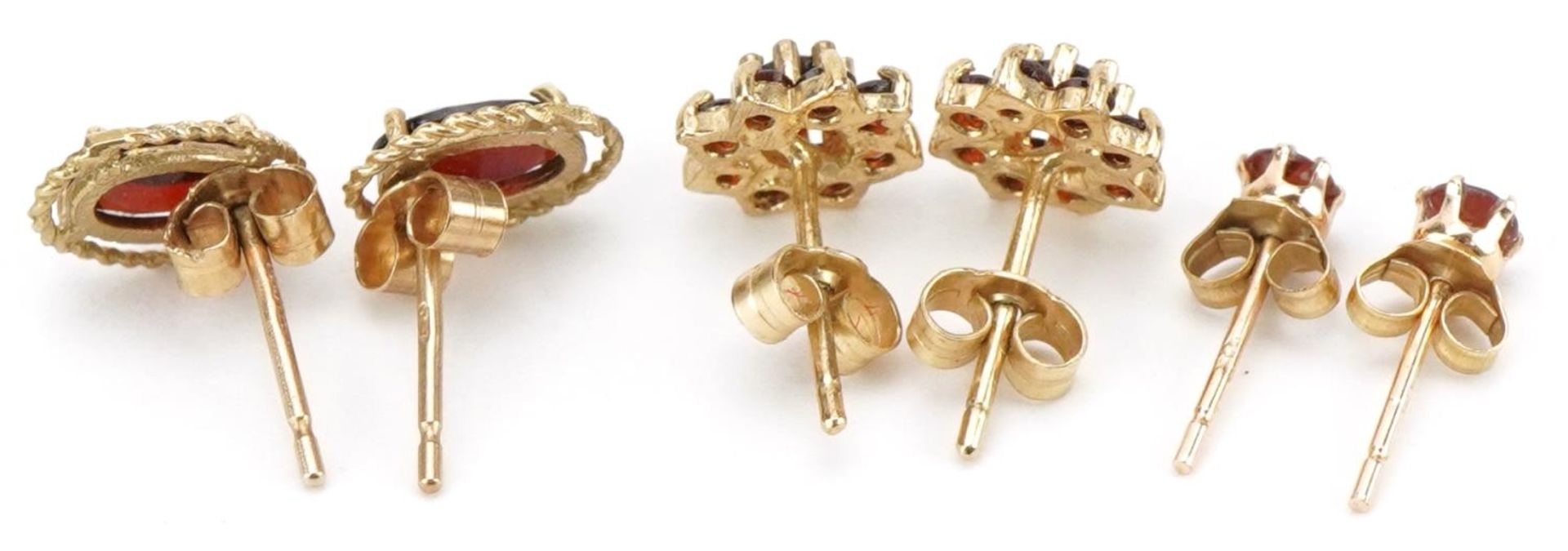 Three pairs of 9ct gold garnet earrings comprising solitaire studs and flower head clusters, the - Image 2 of 2