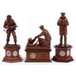 Three bronzed commemorative military figures raised on wooden bases set with coins and medallions by