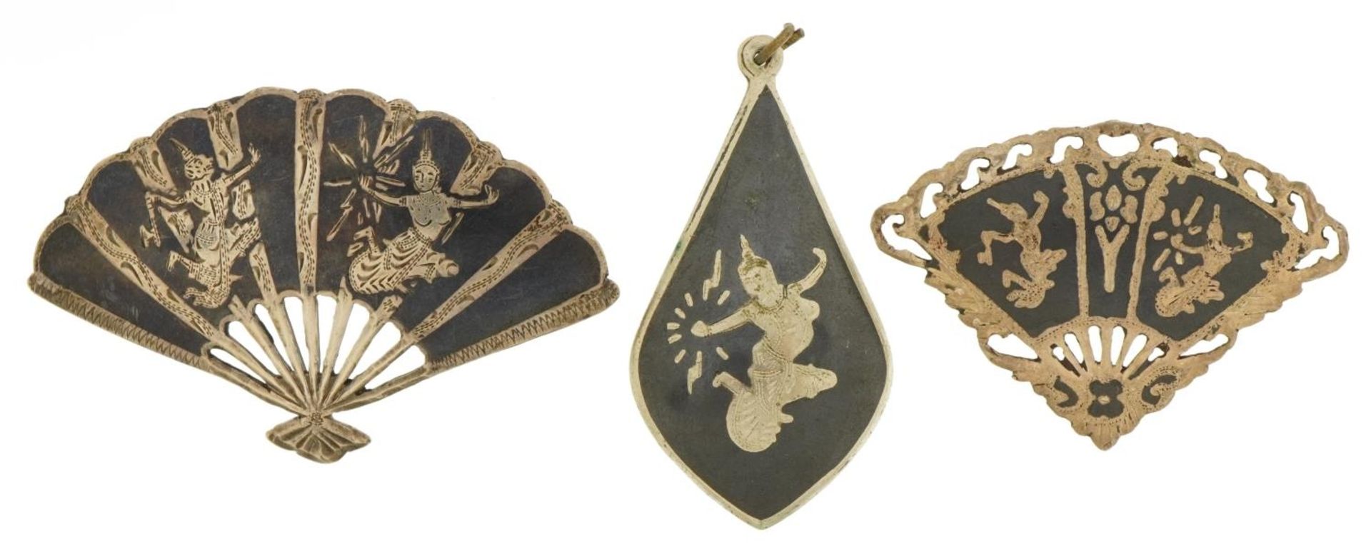 Two Thai Siam fan brooches with niello work dancers and a similar pendant, the largest 5.5cm wide,