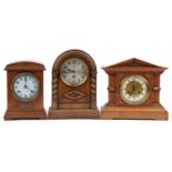 Three oak mantle clocks including one with carved Corinthian columns by Junghans, the largest 36cm